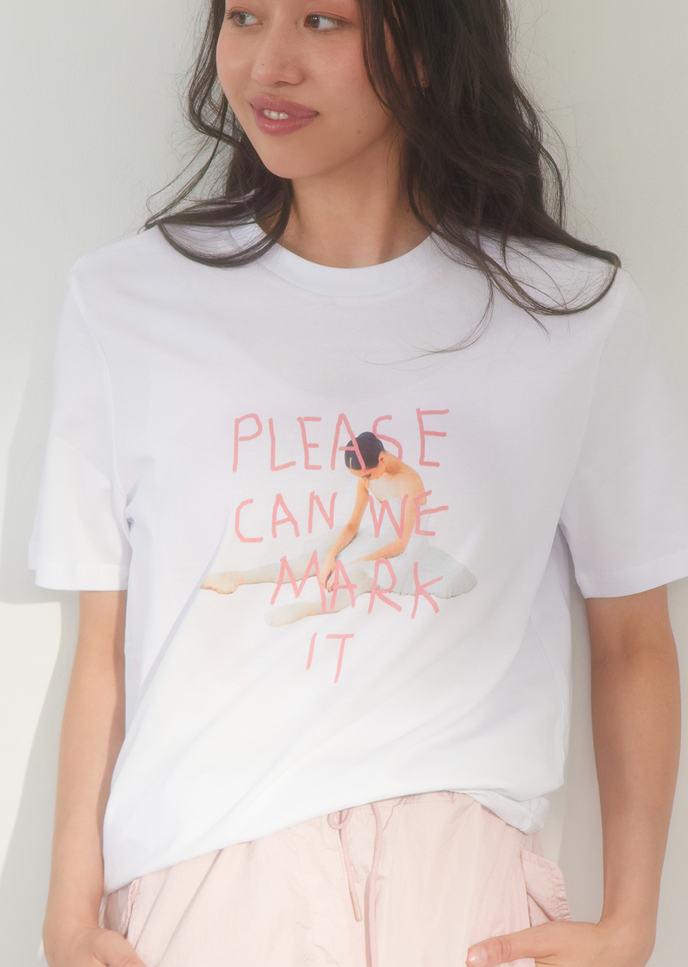 Person wearing a white t-shirt with a graphic and text, standing against a plain background.