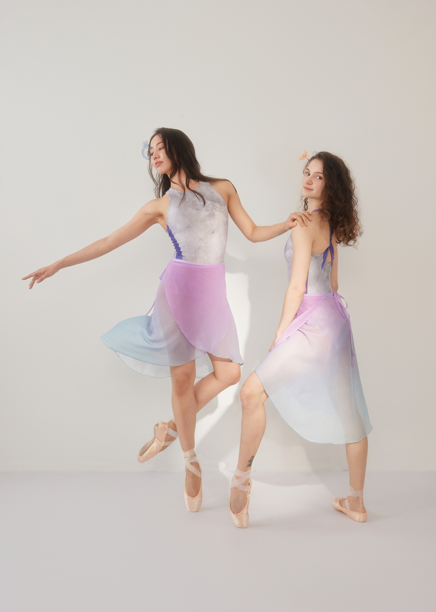 Two dancers in pastel gradient ballet costumes posing against a plain background.