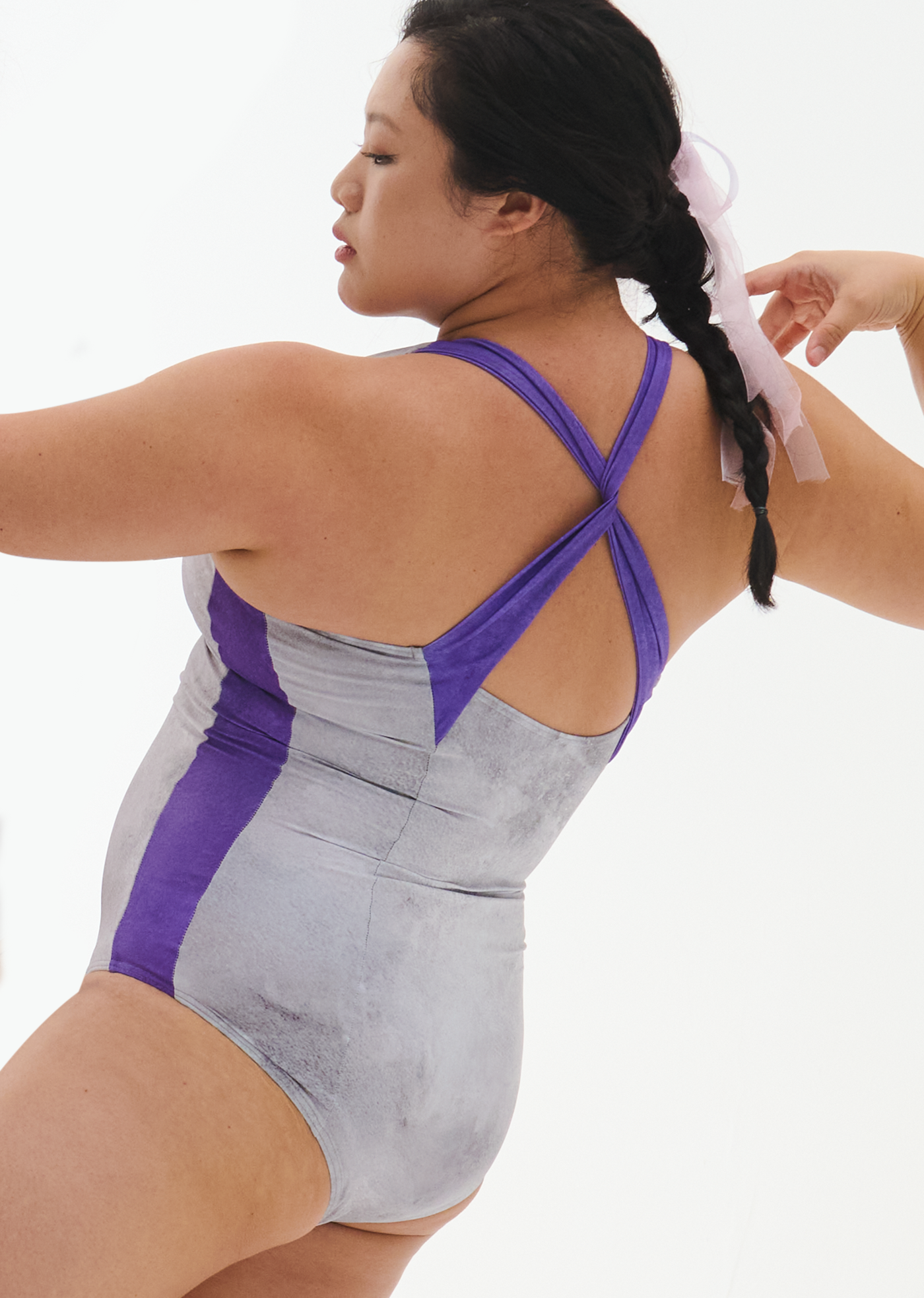 Person wearing a gray and purple swimsuit on a white background