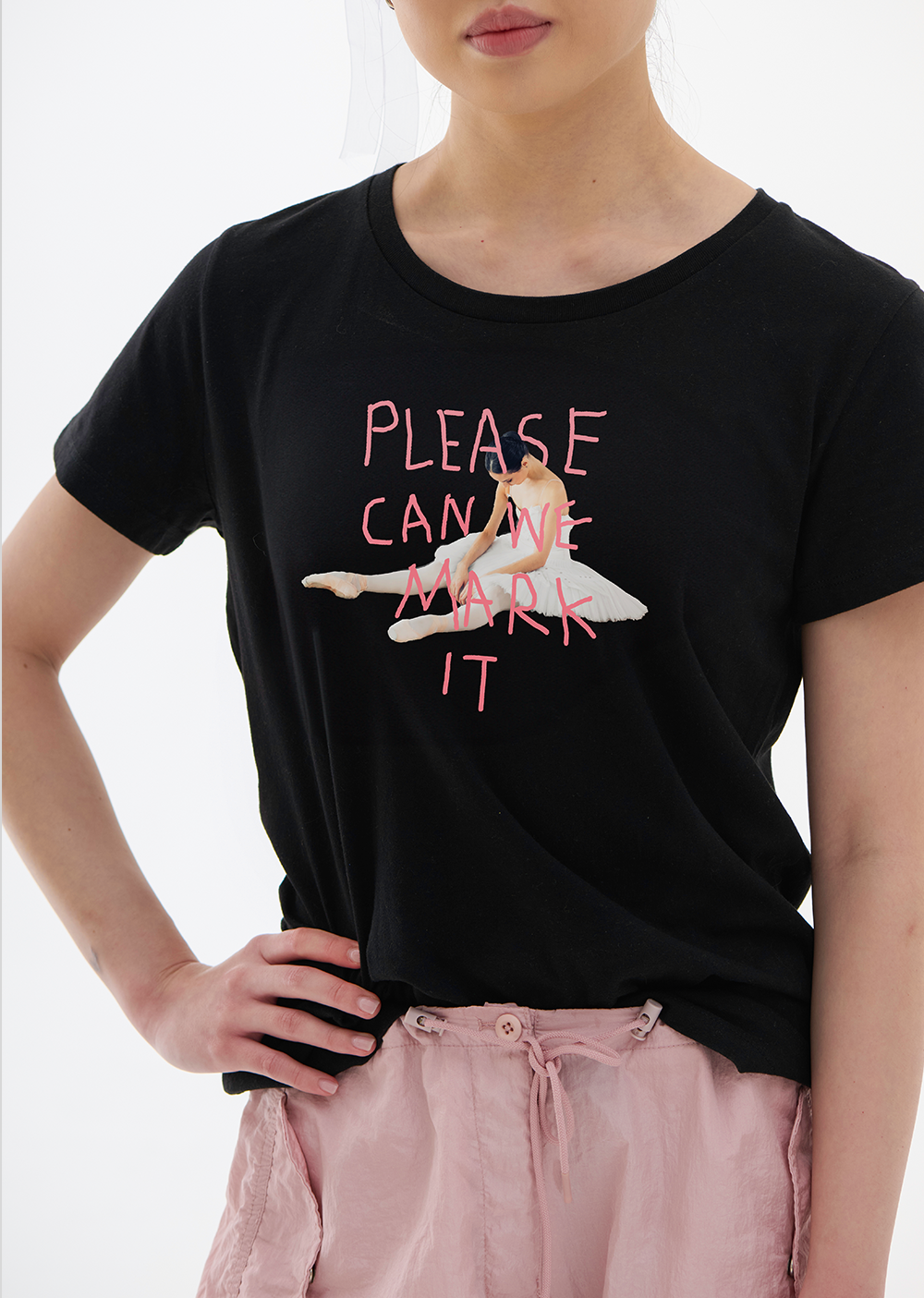 Person wearing a black t-shirt with pink text and graphics on a white background